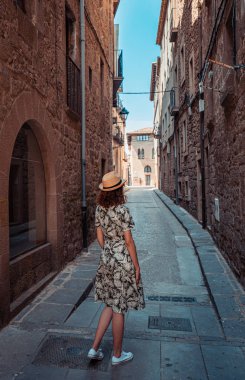 Solsona bir sokakta yürüyen genç bir kadının arka görünümü, Ispanya.