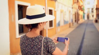 Alicante, İspanya, Denia dar bir cadde resmi alarak saman güneş şapkası ile turist kadın.