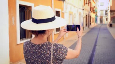 Alicante, İspanya, Denia dar bir cadde resmi alarak saman güneş şapkası ile turist kadın.