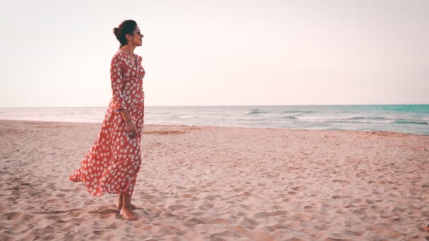 Αργή όψη της όμορφης γυναίκας με κόκκινο φόρεμα χαμογελώντας και κοιτάζοντας τη Μεσόγειο θάλασσα στο ηλιοβασίλεμα — Αρχείο Βίντεο