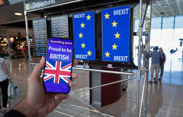 Hand holding a smartphone with UK boarding pass on the screen and EU flag on the info panels representing the Brexit. — Stock Photo, Image