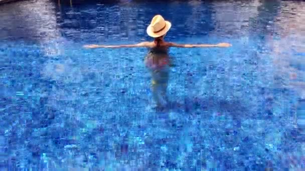Женщина с солнцезащитной шляпой отдыхает в бассейне на курорте . — стоковое видео