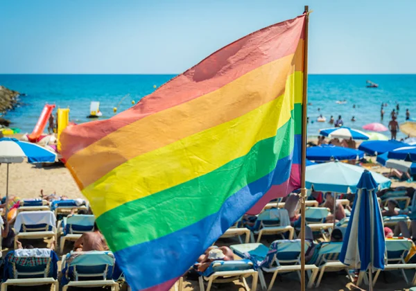 Gay pride vlajka vlající ve větru na pláži Sitges, Španělsko. — Stock fotografie