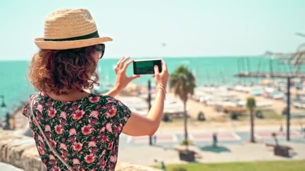 Vrouw die een foto neemt met de Middellandse Zee op de achtergrond — Stockvideo