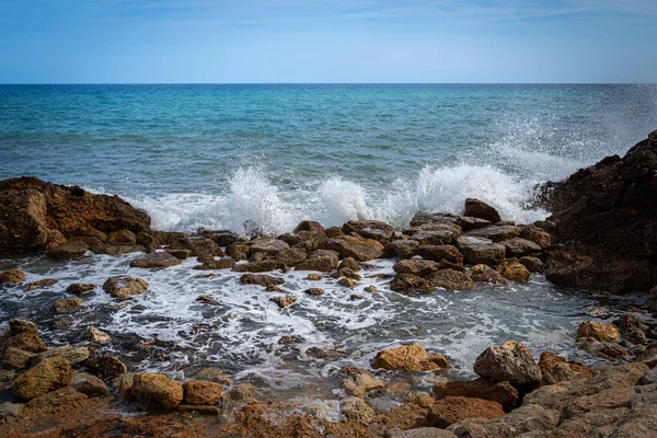 Wellen brechen an einem steinigen Strand auf und bilden eine große Gischt — Stockfoto