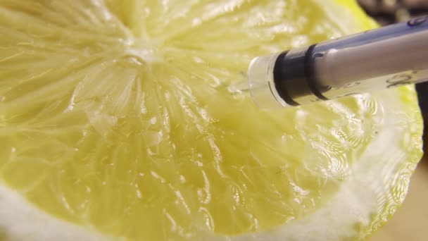 Jeringas que extraen vitamina C del limón . — Vídeo de stock