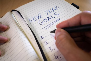 hand writing new years resolutions in a notebook clipart