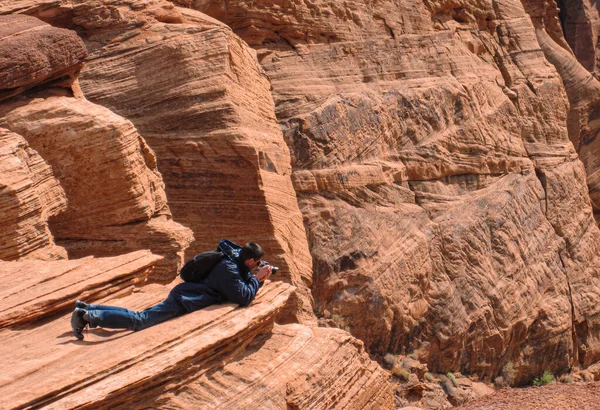 Fotograf ležící na pískovci a fotící. — Stock fotografie