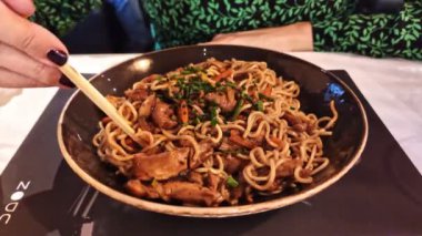 Yemek çubuklarıyla Yaki Soba eriştesi yiyen kadın.