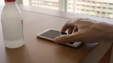 Bakteri ya da koronavirüsten korunmak için e ile akıllı telefon ekranı temizleniyor.