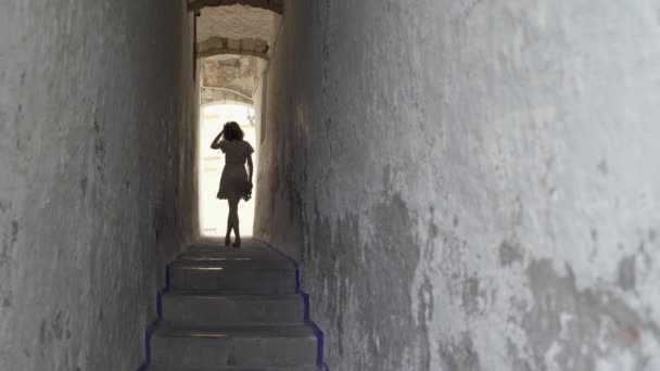 Belle voyageur brune bouclée marchant sur l'étroite rue du correlo de la rectoria à Sitges, Espagne. — Video