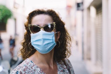 Barcelona 'nın Akdeniz köyü Sitges' de cerrahi maskeli güzel kıvırcık esmer turist.