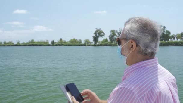 Старший турист фотографируется со своим смартфоном и носит одноразовую маску для лица. — стоковое видео