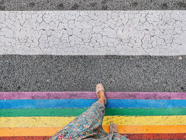 Mujer cruzando un paso peatonal con los colores de la bandera LGTBI. — Foto de Stock
