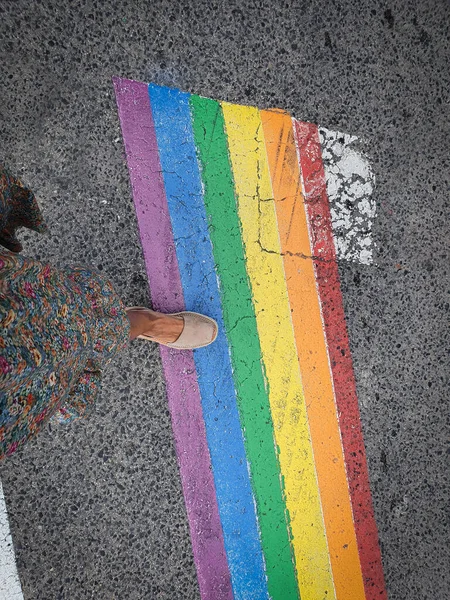 Mujer cruzando un paso peatonal con los colores de la bandera LGTBI. — Foto de Stock