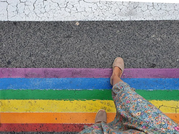 Mujer cruzando un paso peatonal con los colores de la bandera LGTBI. — Foto de Stock