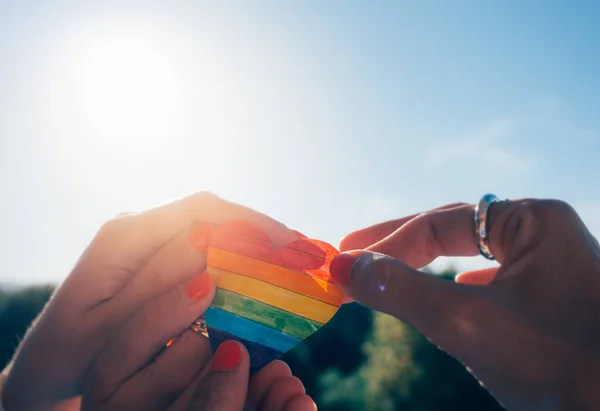 Lesbiana pareja cogida de la mano y un arco iris corazón — Foto de Stock
