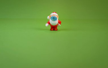 Yüzü cerrahi maskeli Noel Baba oyuncağı figürü.