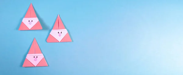 Drei Origami-Weihnachtsmänner auf blauem Hintergrund — Stockfoto