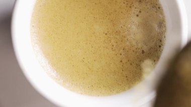 Kahverengi şekeri kremalı bir fincan kahveye dökme görüntüsünün dikey videosu