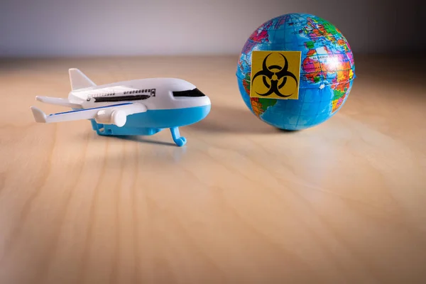 Spielzeugflugzeug neben einer Weltkugel mit dem Biohazard-Symbol — Stockfoto