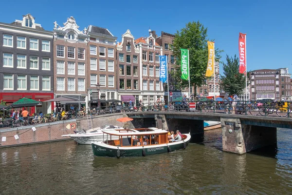 Turistas haciendo turismo viaje en barco de lanzamiento en los canales de Amsterdam — Foto de Stock