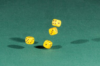 Dört sarı dices yeşil bir masanın üzerine düşüyor