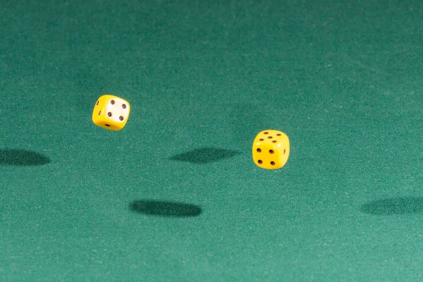 Dois dados amarelos caindo em uma mesa verde — Fotografia de Stock