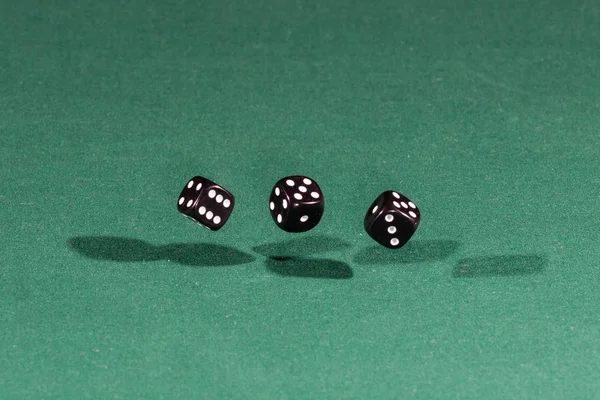 Τρεις μαύρες ζάρια που υπάγονται σε ένα πράσινο τραπέζι — Φωτογραφία Αρχείου