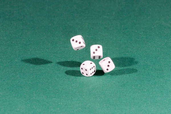 Quatro dados brancos caindo em uma mesa verde — Fotografia de Stock