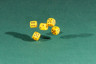 Yeşil bir masanın üzerine düşen beş sarı dices