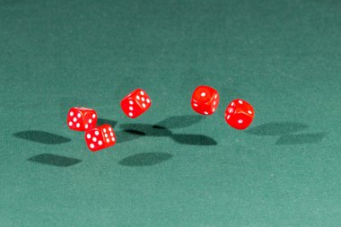 Yeşil bir masanın üzerine düşen beş kırmızı dices