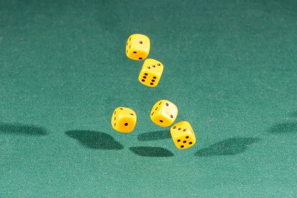 Pět žluté kostky klesá na zeleném stole — Stock fotografie