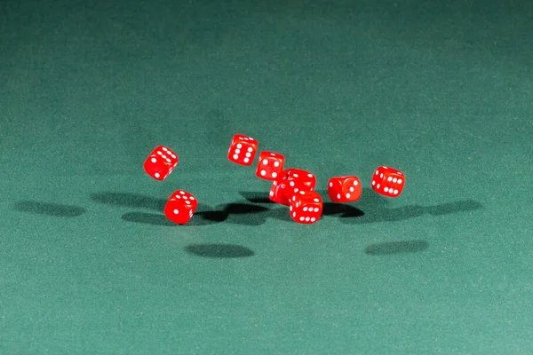 Dez dados vermelhos caindo em uma mesa verde — Fotografia de Stock