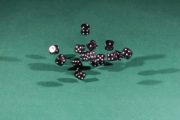 Δεκαπέντε μαύρο ζάρια που υπάγονται σε ένα πράσινο τραπέζι — Φωτογραφία Αρχείου