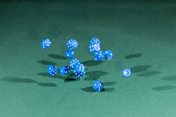 Patnáct modré kostky klesá na zeleném stole — Stock fotografie