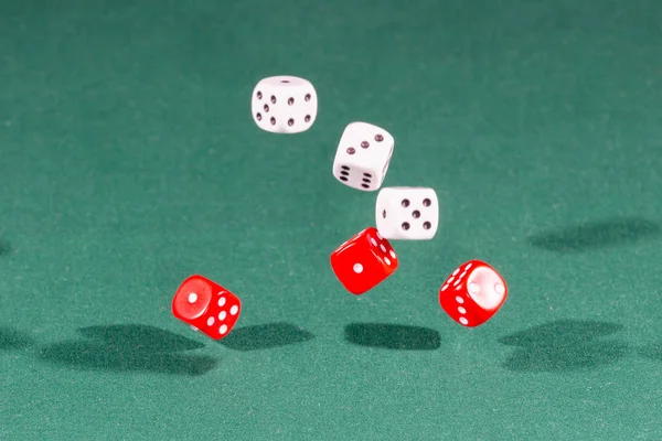Šest červených a bílých kostek spadající na zeleném stole — Stock fotografie