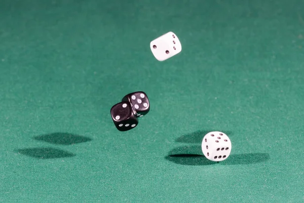 Quatro dados brancos e pretos caindo em uma mesa verde — Fotografia de Stock