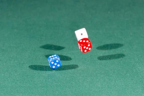 Белые, красные и синие кубики падают на зеленый стол — стоковое фото