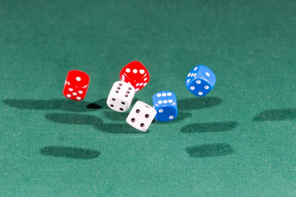 落在绿色桌子上的白色、红色和蓝色的骰子 — 图库照片