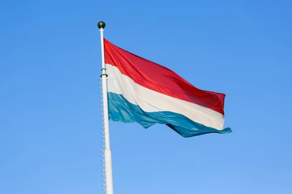 Флаг Люксембурга, размахивающий ветром против голубого неба — стоковое фото