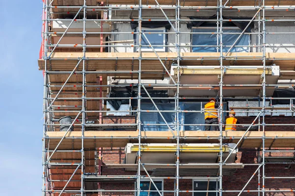 Byggarbetsplats nya hyreshus med byggnadsställningar och murare arbetare — Stockfoto
