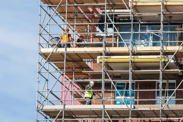 Construcción nuevo edificio de apartamentos con andamios y albañiles — Foto de Stock