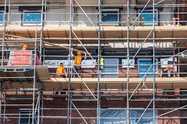 Byggarbetsplats nya hyreshus med byggnadsställningar och murare arbetare — Stockfoto