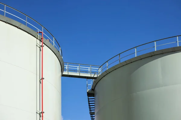 Mavi gökyüzüne karşı podyum köprüsü olan yakıt depolama tankları — Stok fotoğraf