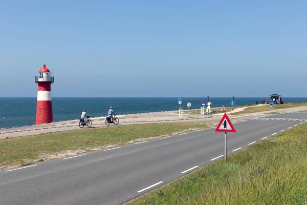 Farul la dike cu motocicliști care trec pe lângă Westkapelle, Olanda — Fotografie, imagine de stoc