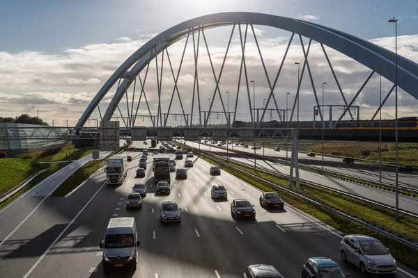 Auto-estrada holandesa perto de Amesterdão com ponte ferroviária e comboio de passagem Imagens De Bancos De Imagens