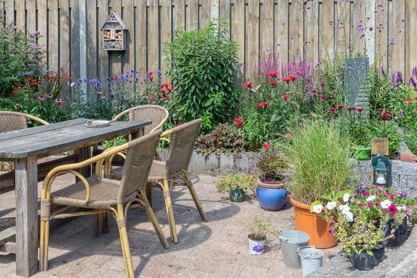 Ziergarten mit bunten Pflanzen im Beet und Holztisch — Stockfoto