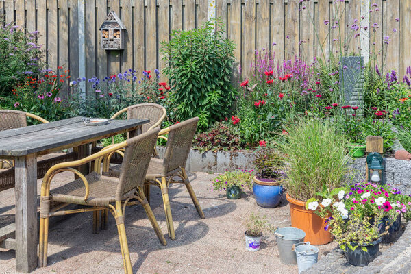 Ornamental garden with colorful plants in flowerbed and wooden table