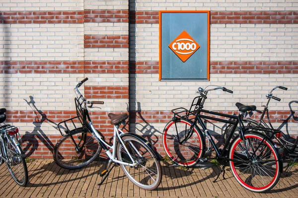 Bicicletas estacionadas contra pared con valla publicitaria del supermercado holandés C1000 — Foto de Stock